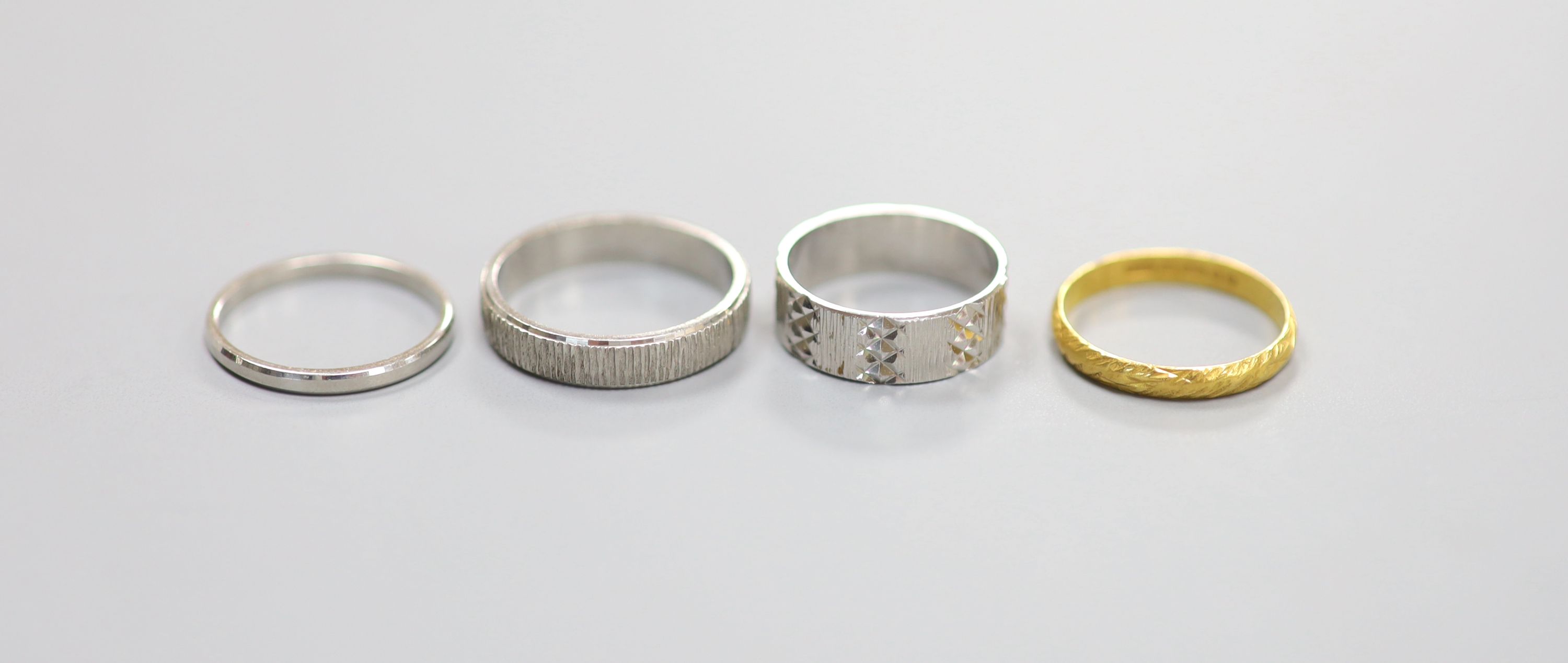 Two platinum wedding bands, 7.8 grams, an 18ct white gold wedding band, 3.7 grams and a 22ct gold band, 1.8 grams.